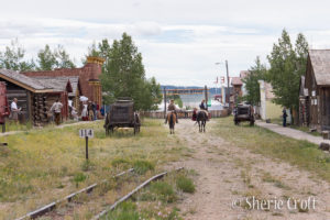 Restored 1800's historical town, South Park City with 2 cowboys on horses and an old wagon in the street.