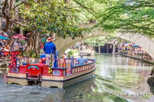 A River Cruise boat heads down the river for a tour of the River Walk and water way of San Antonio, Texas.