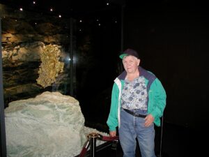 My name artist nugget standing next to a giant gold nugget.